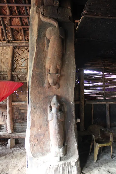 Carved wooden post with animal figures inside a traditional house